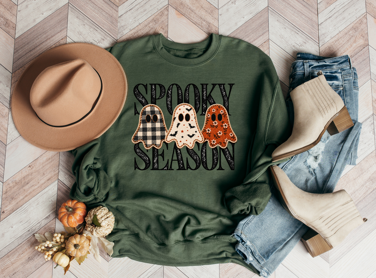 Spooky Season lettering and three patterned ghosts with a printed stitched effect on a green sweatshirt