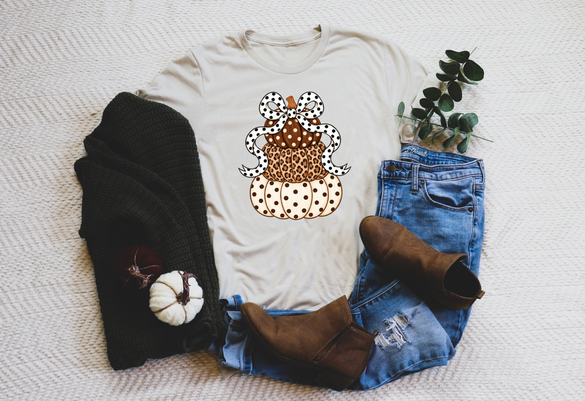 Stacked leopard and polka dot pumpkins with a black and white bow on a cream tee